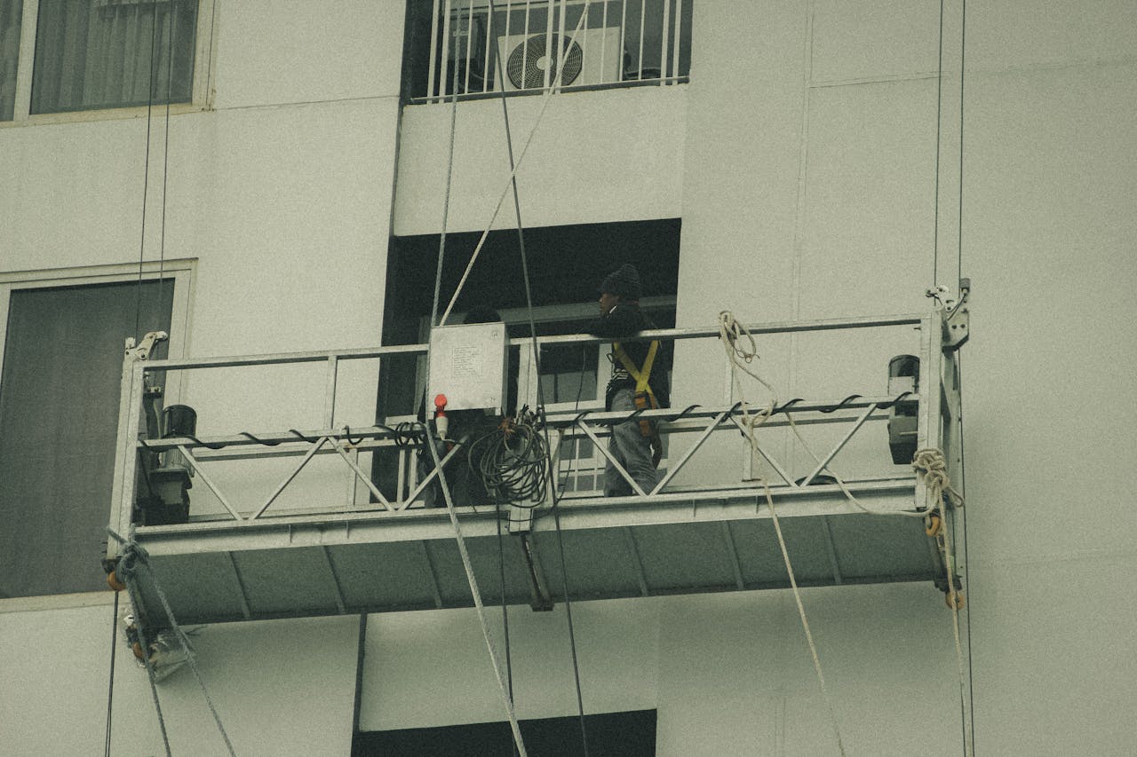 Anasayfa A worker on a suspended scaffold is repairing a building facade.